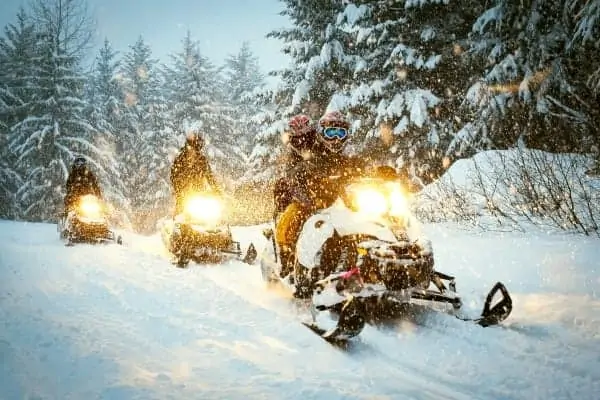 Snowmobiles in blizzard through the forest