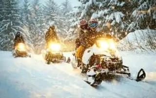 Three snomobilers in heavy snowfall.