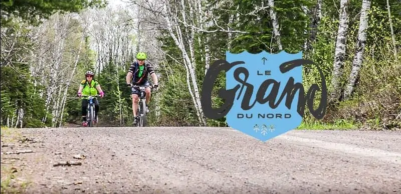 Cyclists on a dirt trail. Text: Le Grand Du Nord