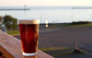Pint of Voyager beer on a deck railing.