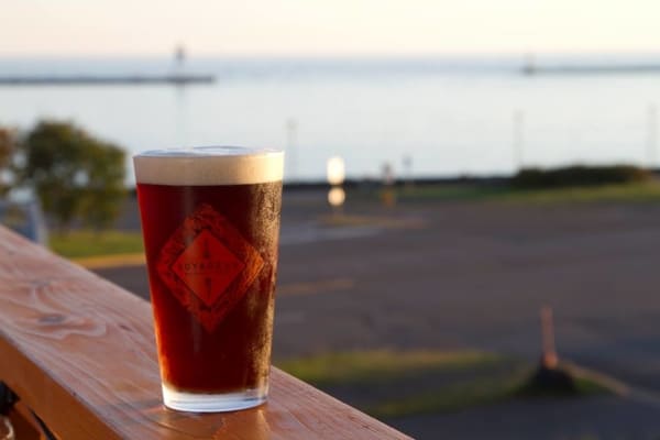 Pint of Voyager beer on a deck railing.