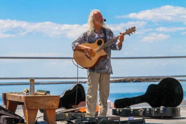 Older man playing guitar on the boardwalk.