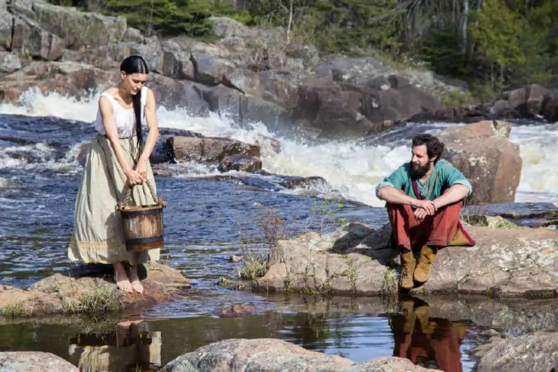 Man and woman in a river with a water pail.