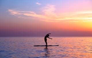 Yoga trainer over sunset background